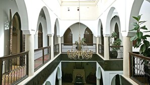 Un interior espacioso con techos altos, puertas en arco y un candelabro central.