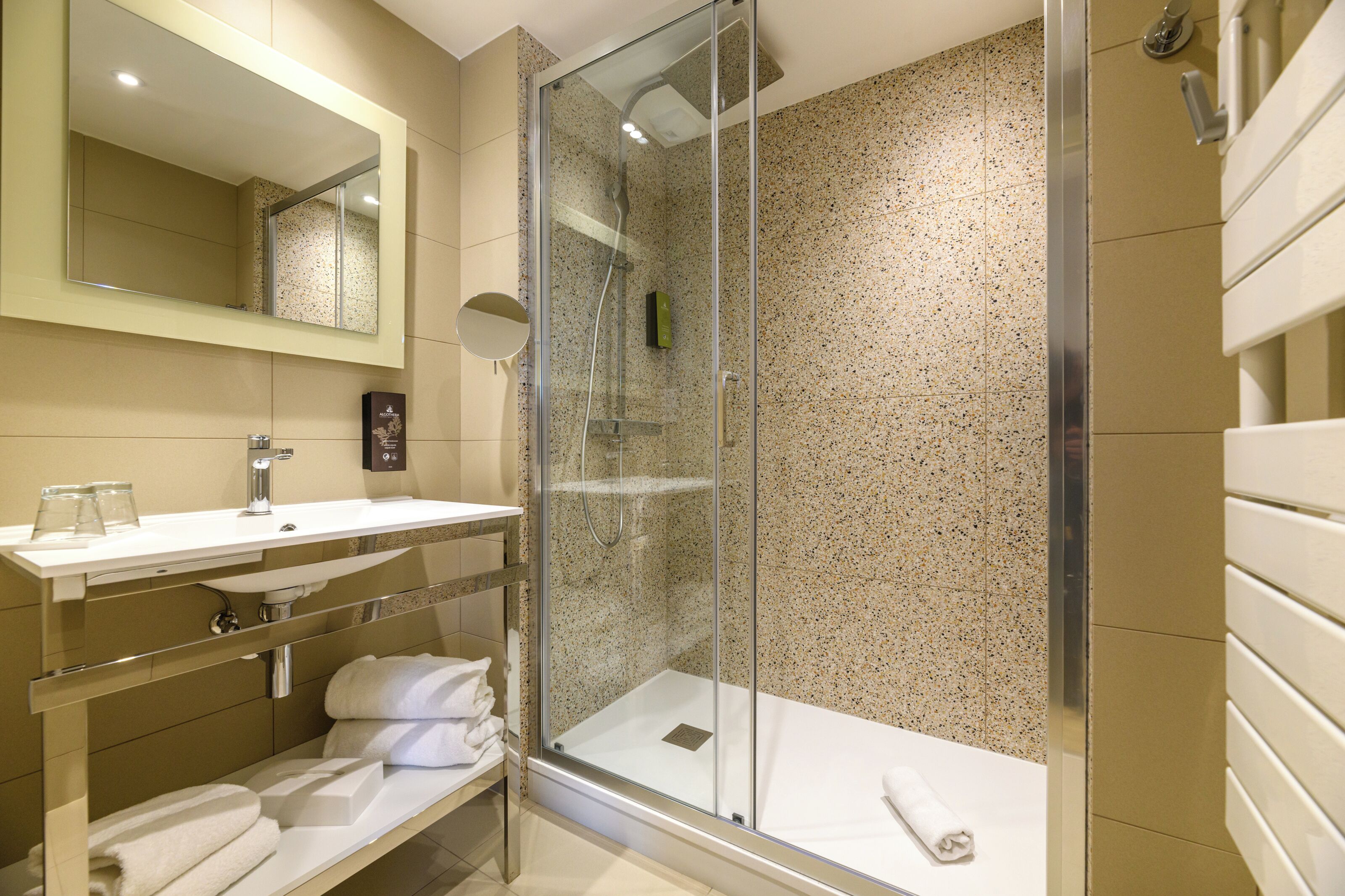 A modern bathroom with a glass-enclosed shower, a white sink, and a large mirror.