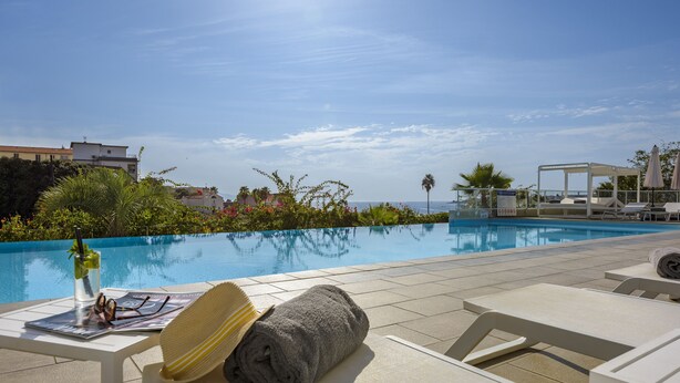 A poolside area with lounge chairs, a sun umbrella, and a pool. - Résidence de Tourisme Ajaccio Amirauté (Ajaccio)