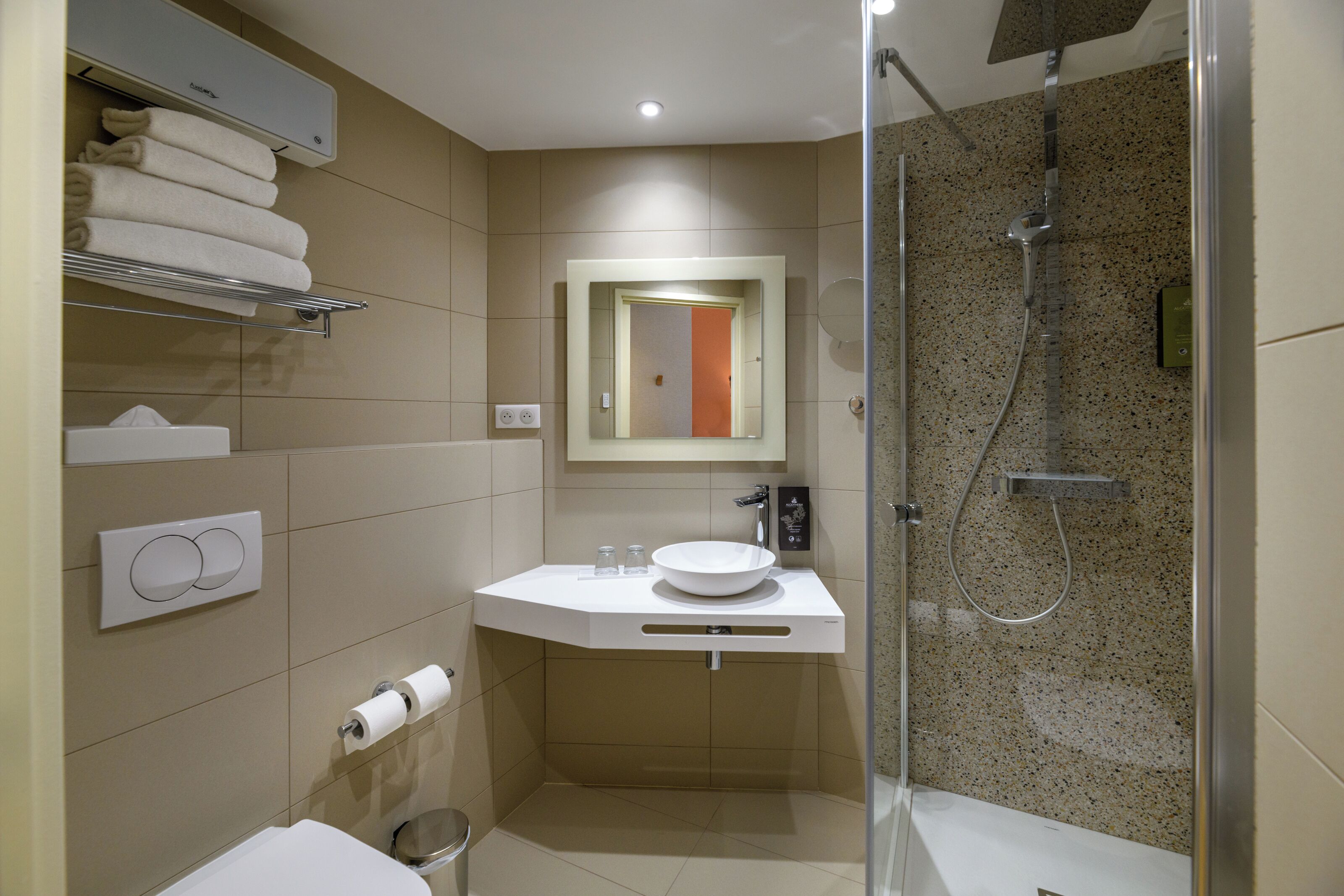 Un baño moderno con cabina de ducha de vidrio, un lavabo blanco y un perchero para toallas.