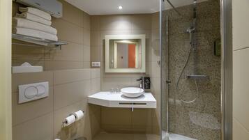 A modern bathroom with a glass-enclosed shower, a white sink, and a towel rack.