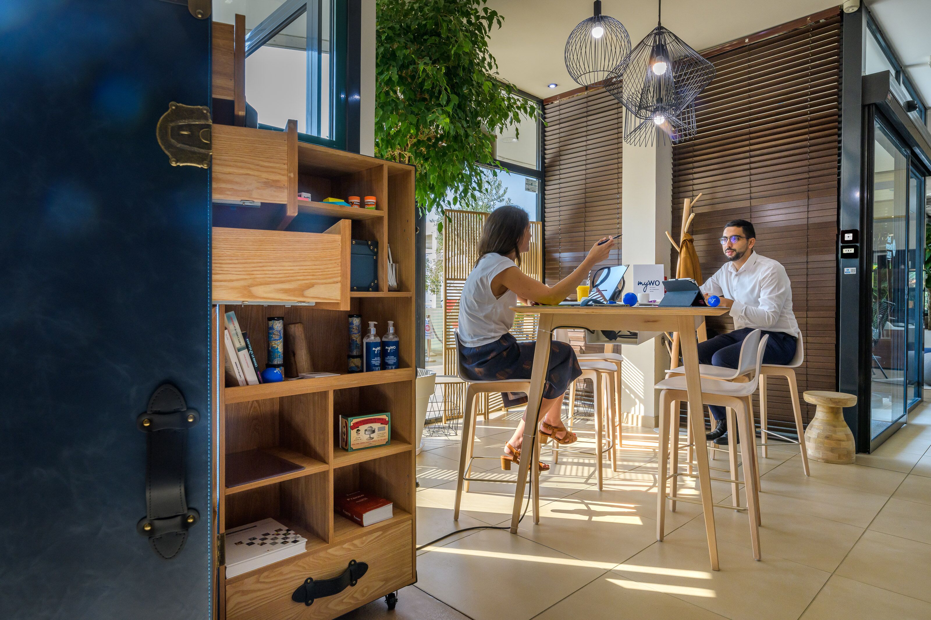A modern interior with a wooden desk, chairs, and a bookshelf.