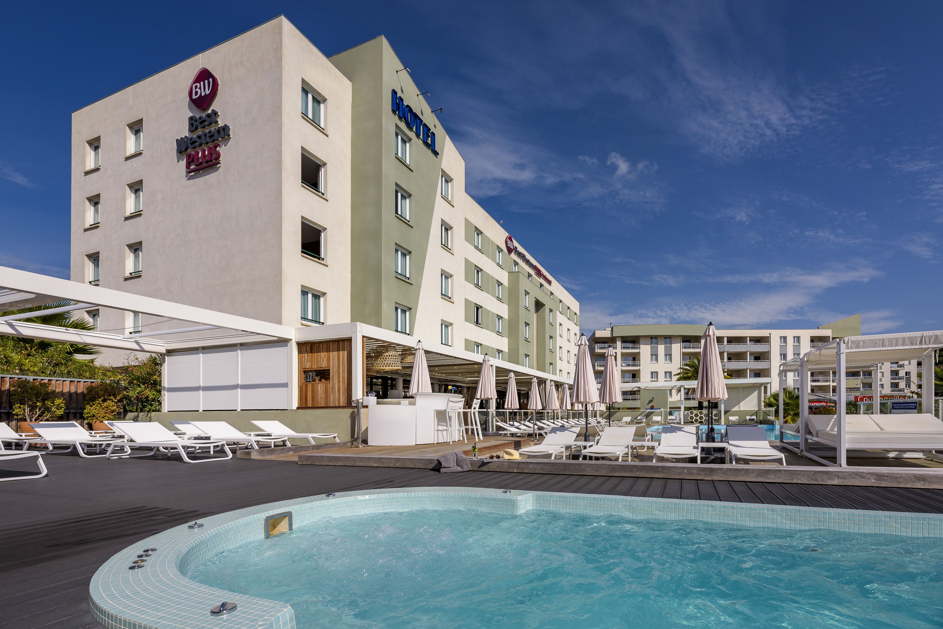 A hotel with a swimming pool, sun loungers, and umbrellas.