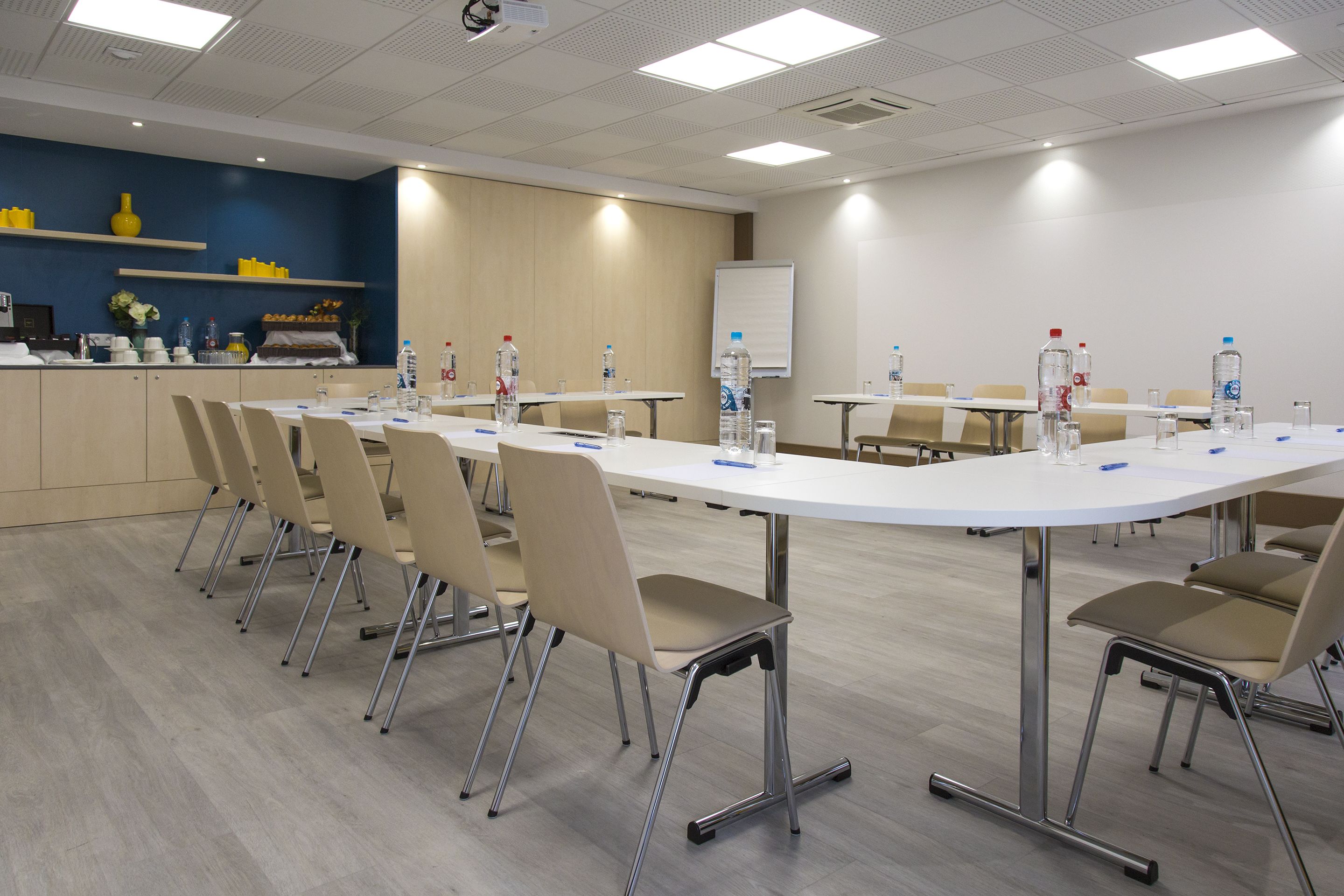 Une salle de conférence avec une longue table, des chaises et des bouteilles d’eau.