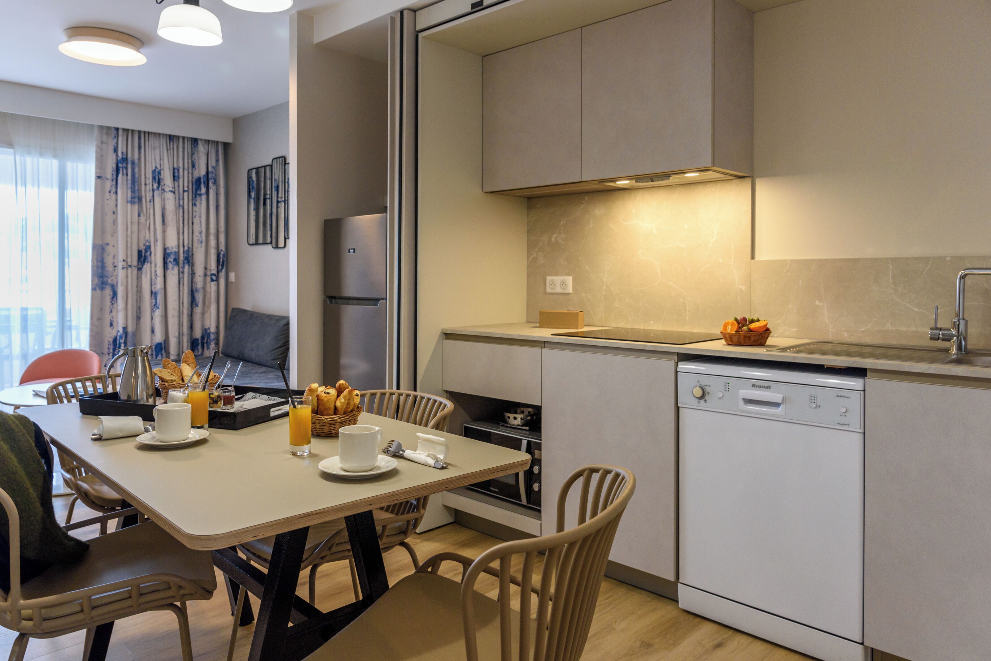 A modern kitchen with a dining area, equipped with a dishwasher, oven, and a built-in microwave.