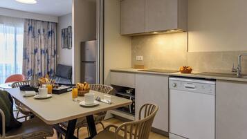 Een moderne keuken met een eetgedeelte, voorzien van een vaatwasser, oven en een inbouwmagnetron.