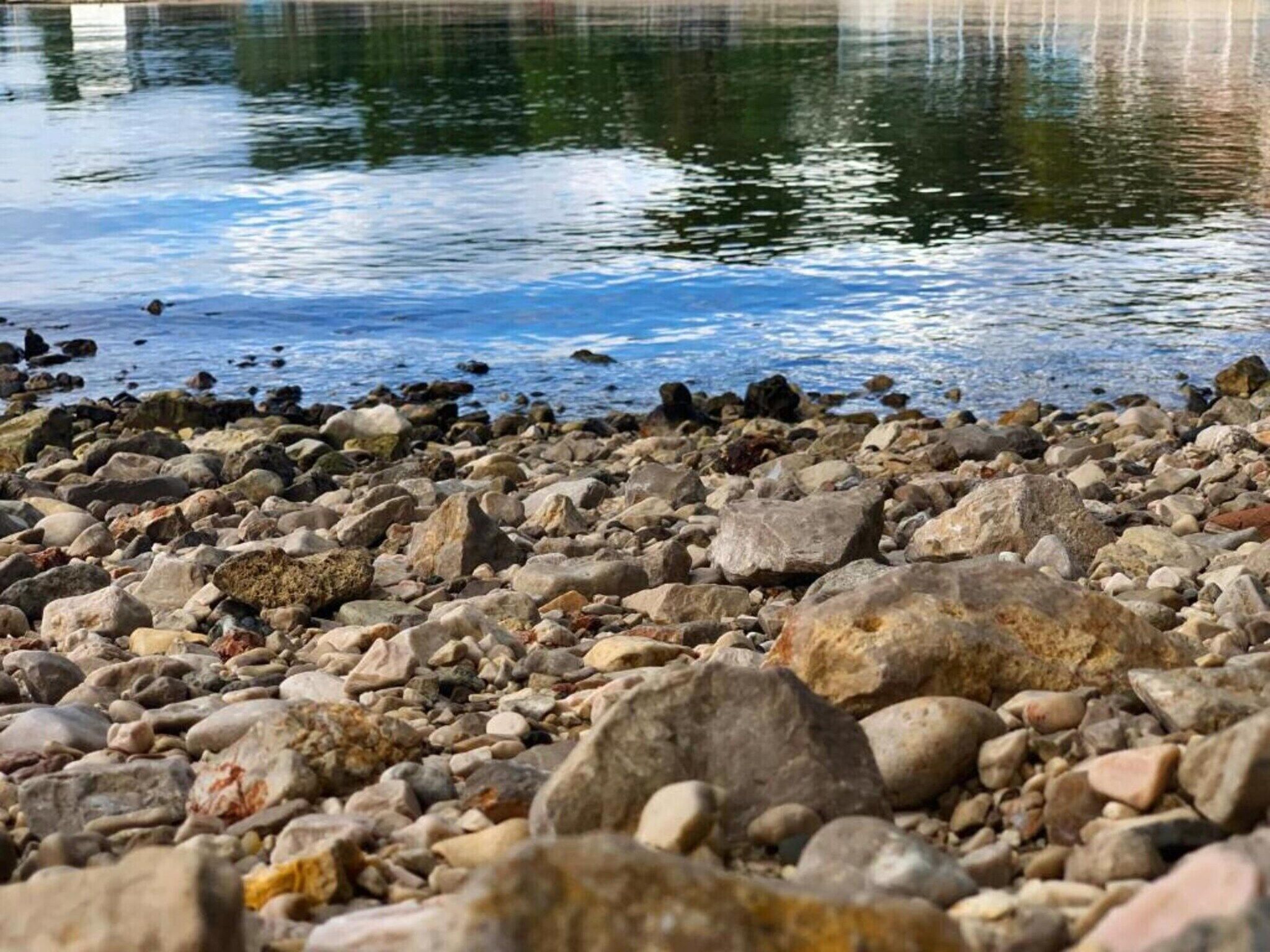 Een rotsachtige kustlijn met een rustig waterlichaam dat de lucht weerspiegelt.