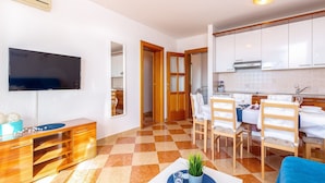 A modern living room with a flat-screen TV, wooden furniture, a dining area with a table and chairs, and a kitchen with white cabinets. - Charming Countryside Escape (Crikvenica)