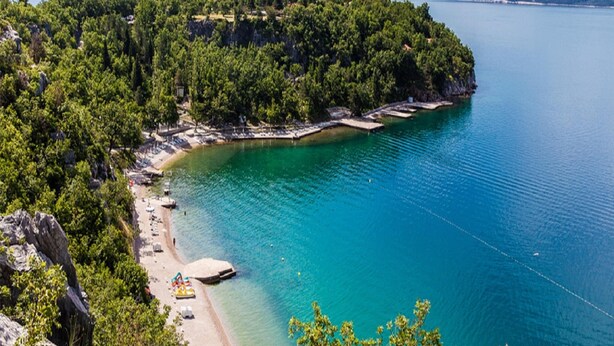 A coastal area with a beach, clear turquoise waters, and a forested peninsula. - Charming Countryside Escape (Crikvenica)