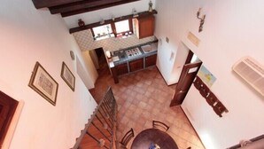 A kitchen with a tiled floor, wooden cabinets, and a window above the sink. - Casa Ifigenia (Cefalù)
