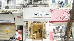 A storefront with a sign reading "Thúc@3am" and a travel service sign.