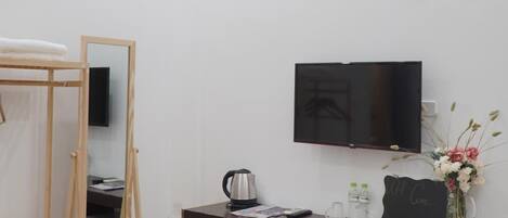 Un dormitorio con una cama litera, un escritorio con televisor, un refrigerador pequeño y un jarrón decorativo.