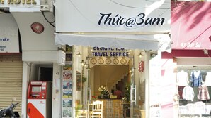 A travel service shop with a staircase leading to a second floor, a motorcycle parked outside, and a visible ATM.