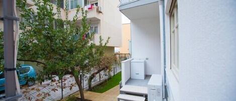 Un edificio residencial con un pequeño jardín, un balcón y una escalera que lleva a la entrada.