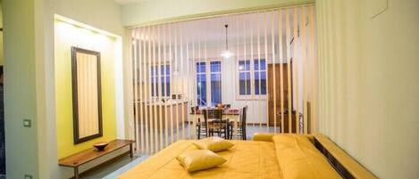 A room with a bed, a bench, a table, and a chair.