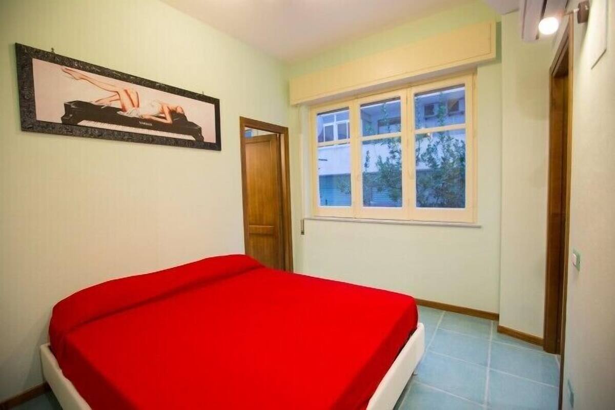 Un dormitorio con una cama individual, una ventana y una puerta.