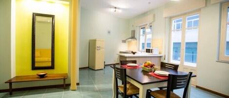 A compact kitchen with a dining area, a bench, and a large window.