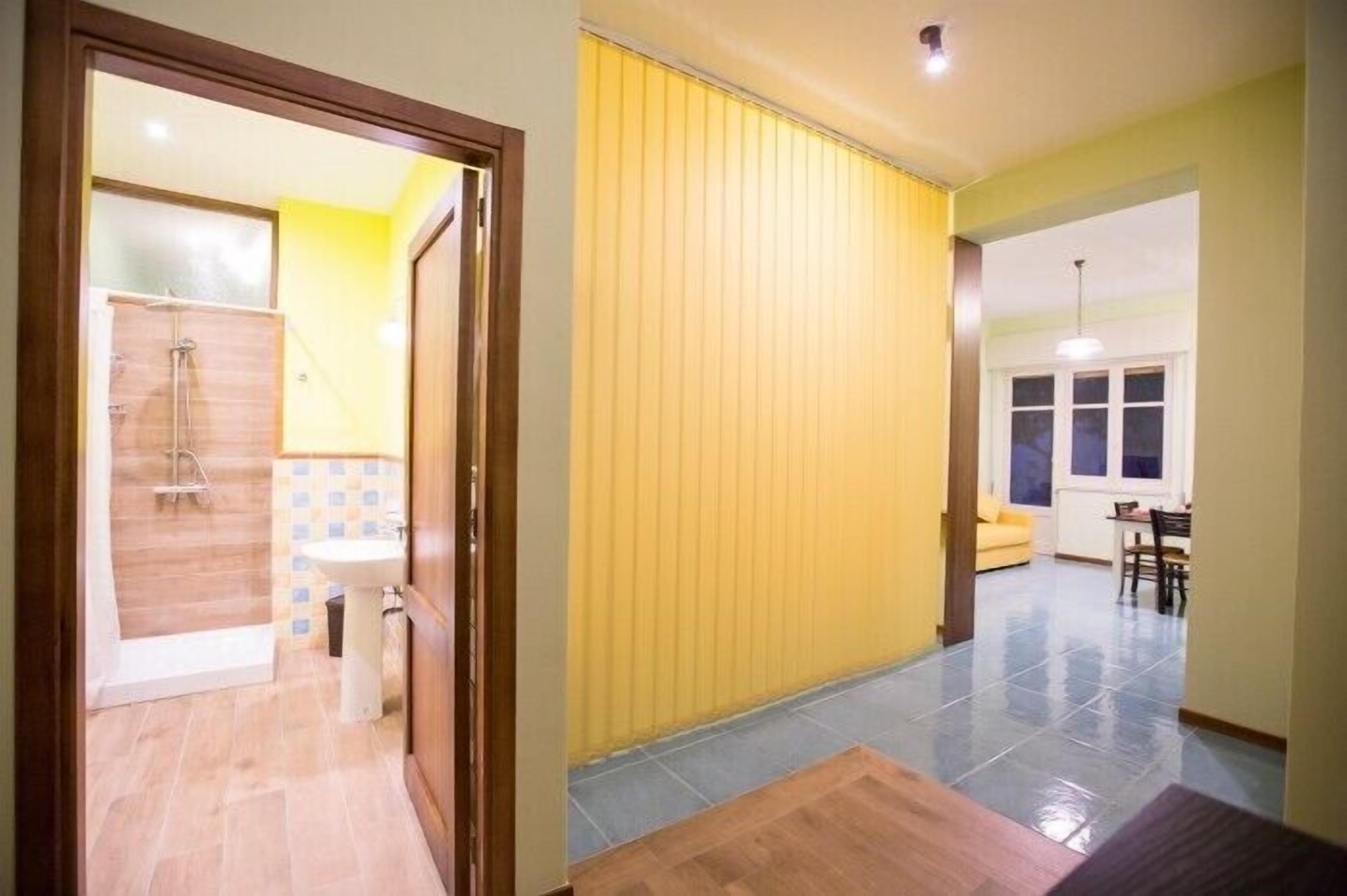 A room with a shower, a sink, and a yellow wall.