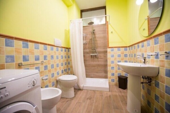 Un baño con ducha, inodoro, lavabo y lavadora.