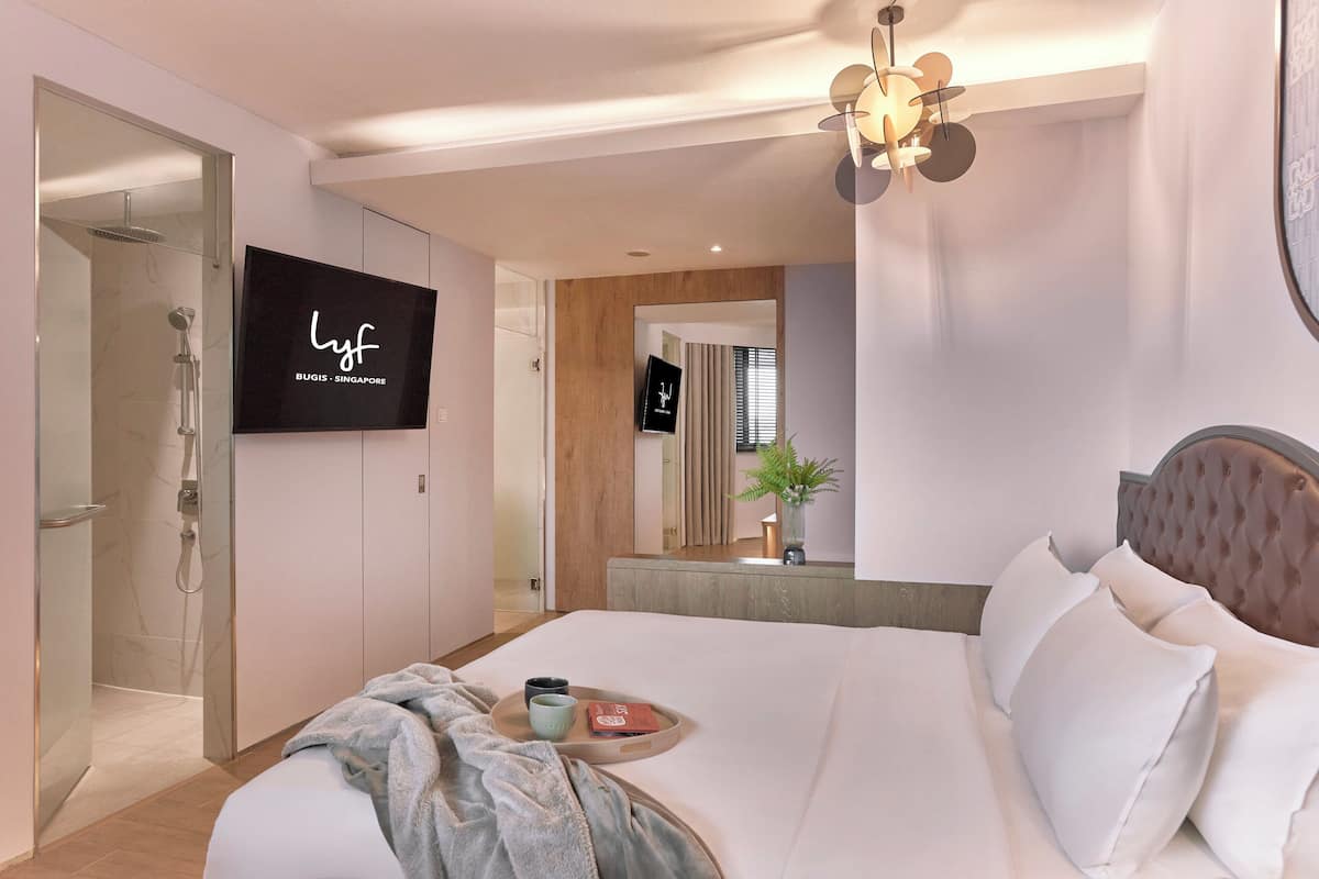 Une chambre d’hôtel moderne équipée d’un grand lit, d’une télévision, d’une douche et d’un miroir.