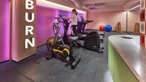 Un gimnasio con cintas de correr, una bicicleta estática y una pared con la palabra 'BURN'.