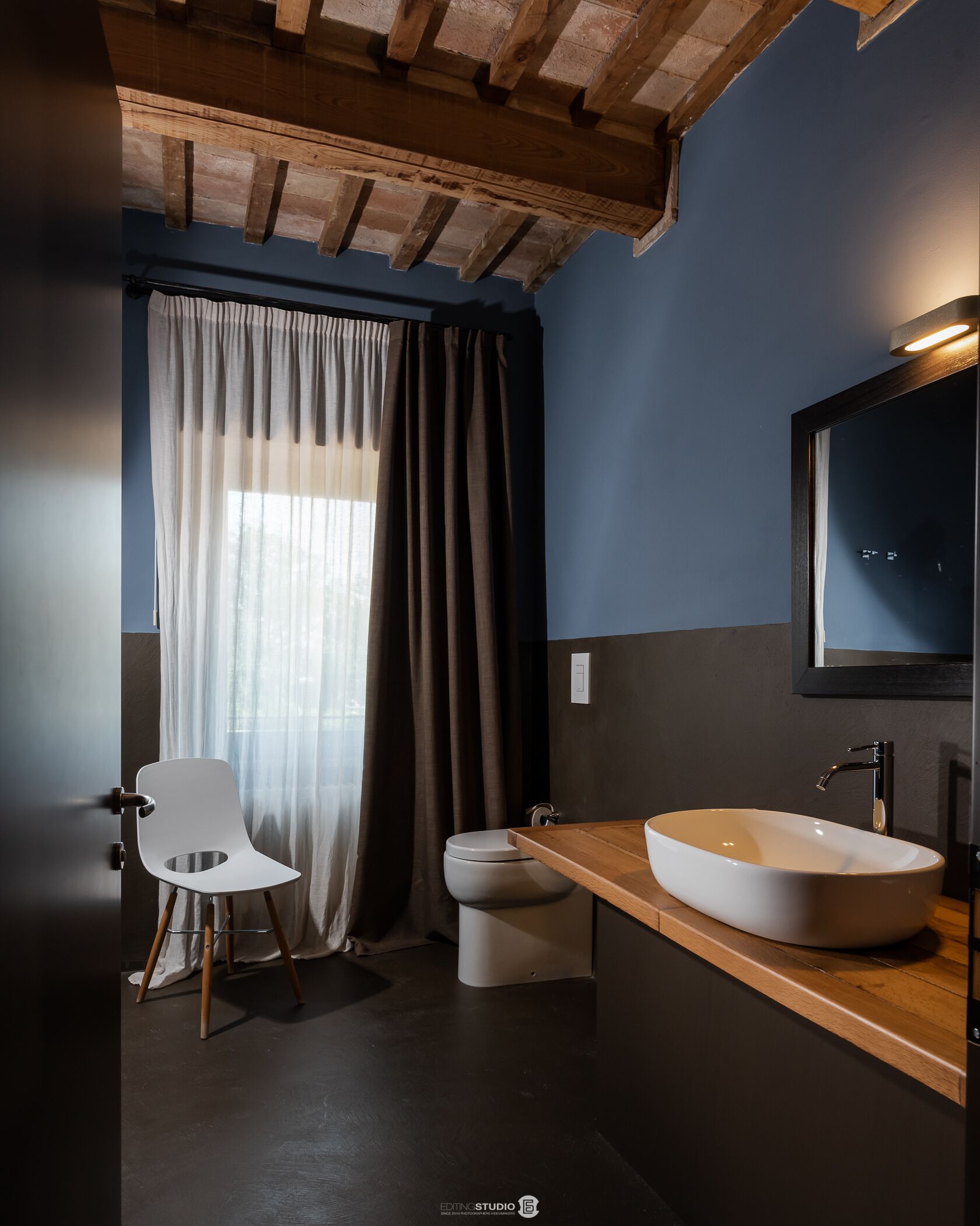 Un baño moderno con tocador de madera, lavamanos blanco y retrete.