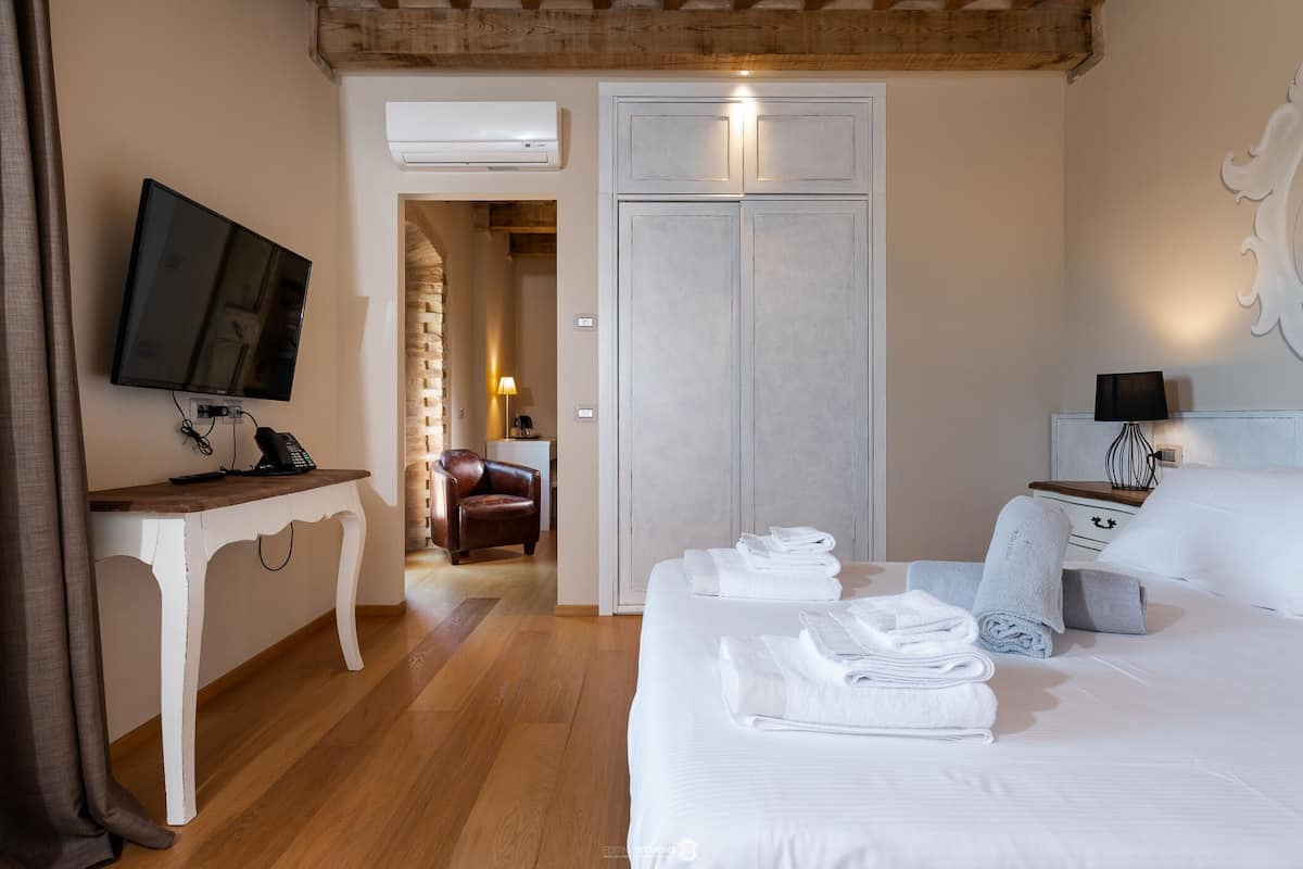 Una habitación de hotel con cama, escritorio, televisión y armario.