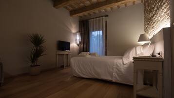 Ein Schlafzimmer mit einem Bett, einem Fernseher, einer Lampe, einem Topf mit Pflanze und einer Holzbalkendecke.