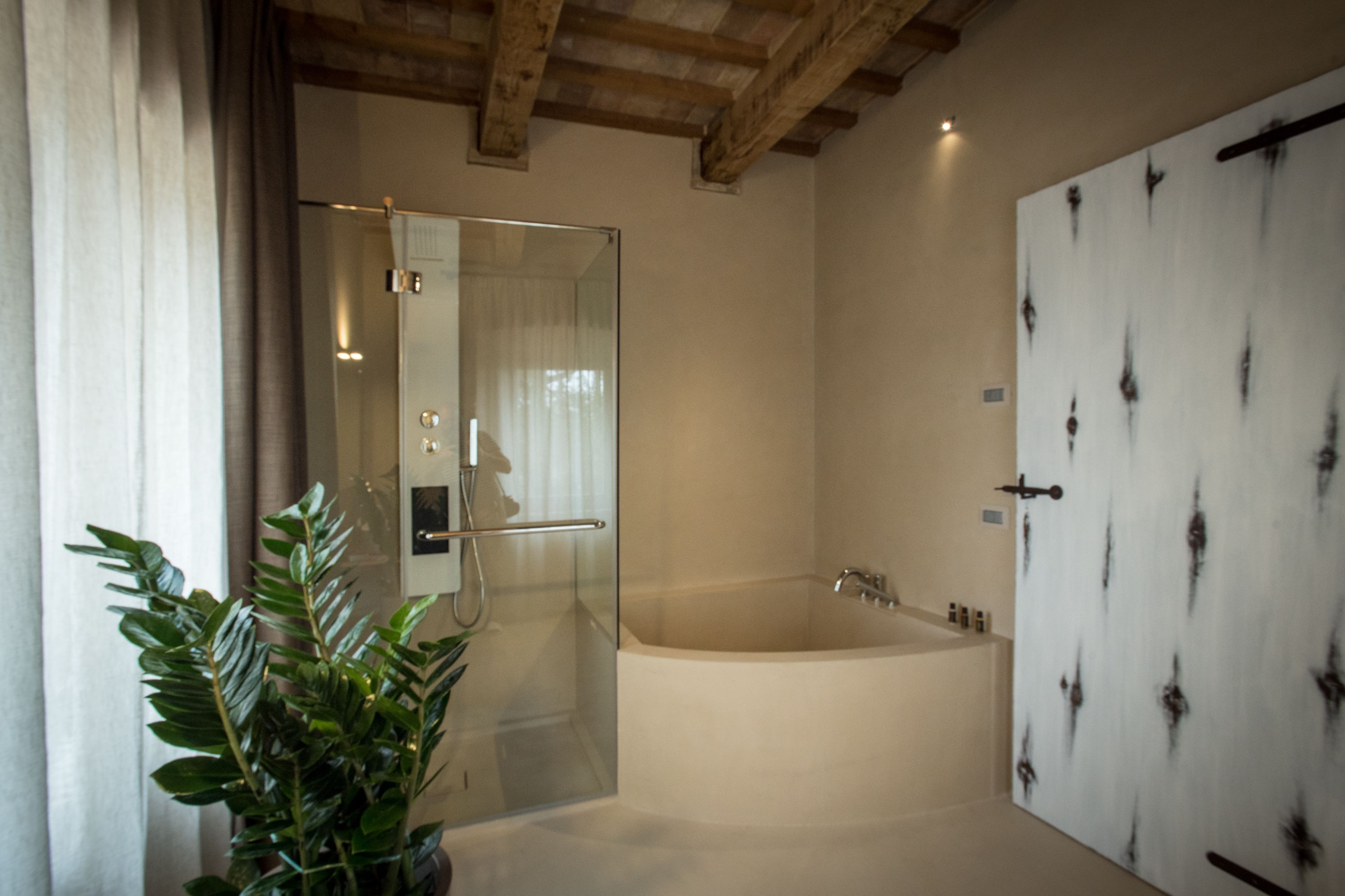 A modern bathroom with a glass-enclosed shower, a freestanding bathtub, and a white door with a unique pattern.