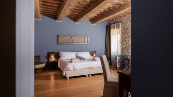 Une chambre avec un plafond en bois, un lit avec des oreillers et une lampe, une chaise et une table sur laquelle se trouve un vase.