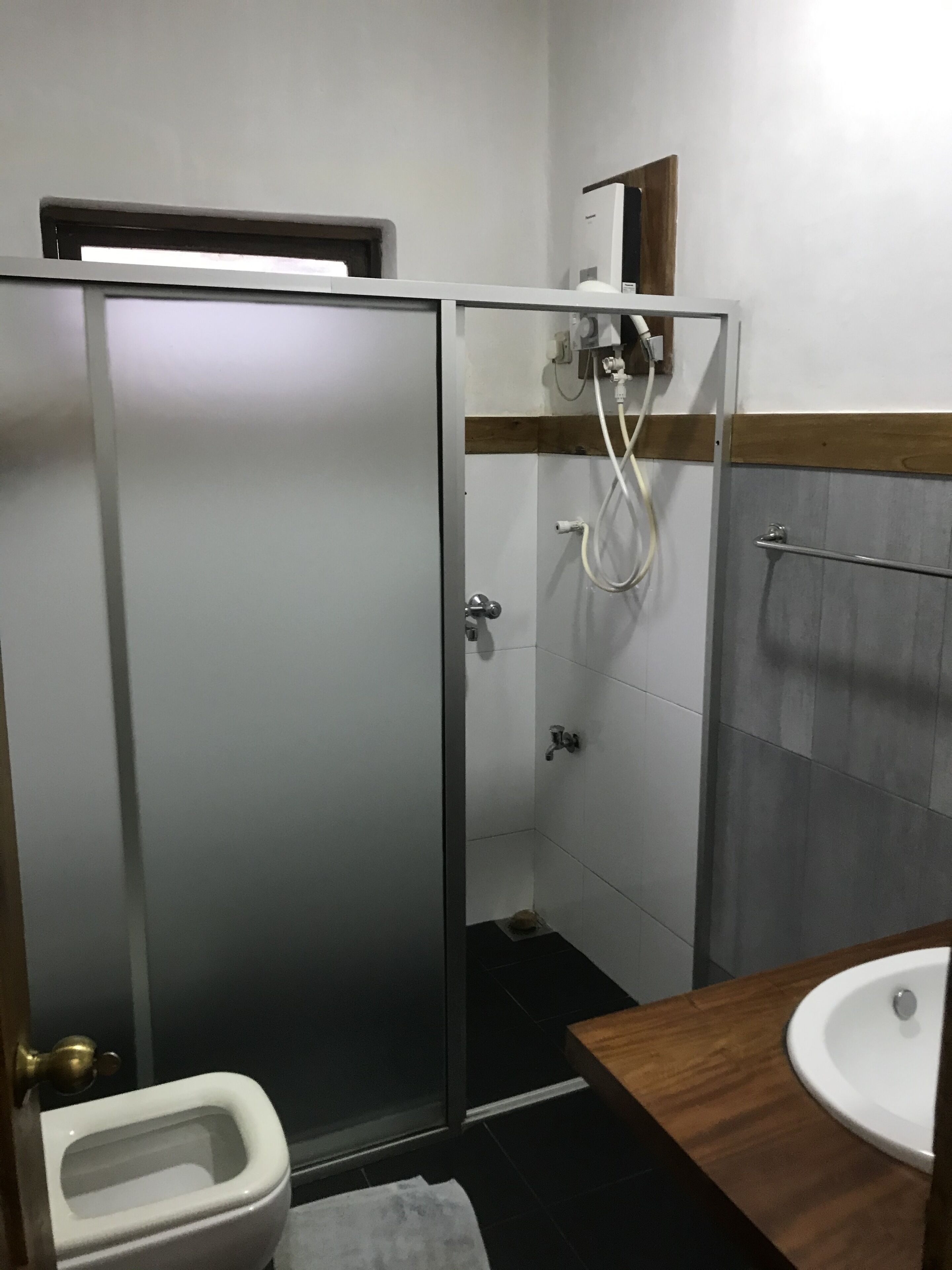 Un baño moderno con ducha envuelta en cristal, un inodoro y un lavamanos.