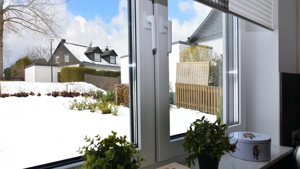 A window with a view of a snowy yard, a wooden box, and two potted plants on a windowsill. - Moderne Villa in Medebach Küstelberg (Medebach Küstelberg)