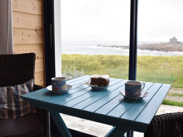 A table with a view of the ocean and a rocky outcrop in the distance.