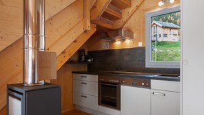 Eine moderne Küche mit Holzbalken, Edelstahlgeräten und Blick auf ein Haus durch ein Fenster.