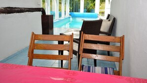 A view of a pool area with wooden chairs and a table, a wooden bench, and a blue cushion. - South Bohemia Family Escape (Bechyne)