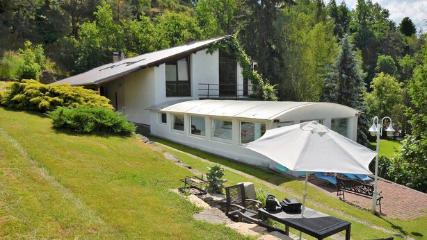 A modern house with a large glass window, surrounded by lush greenery and a well-maintained lawn. - South Bohemia Family Escape (Bechyne)