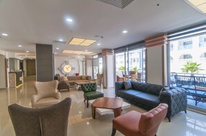A spacious lobby with a reception desk, sofas, and chairs arranged for guests. - Kolibri Hotel (Alanya)
