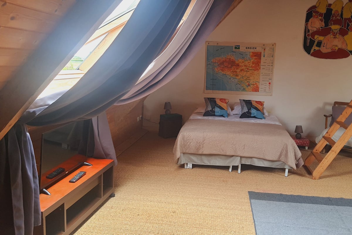 Quarto com cama beliche, escrivaninha com computador, mapa na parede e escada.