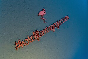 A hashtag #HotelFlamingogiesen on a sandy surface.