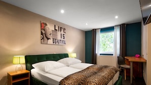 A hotel room with a bed, two bedside lamps, a desk, and a window with curtains. - SmartHotel Flamingo self-check-in (Giessen)