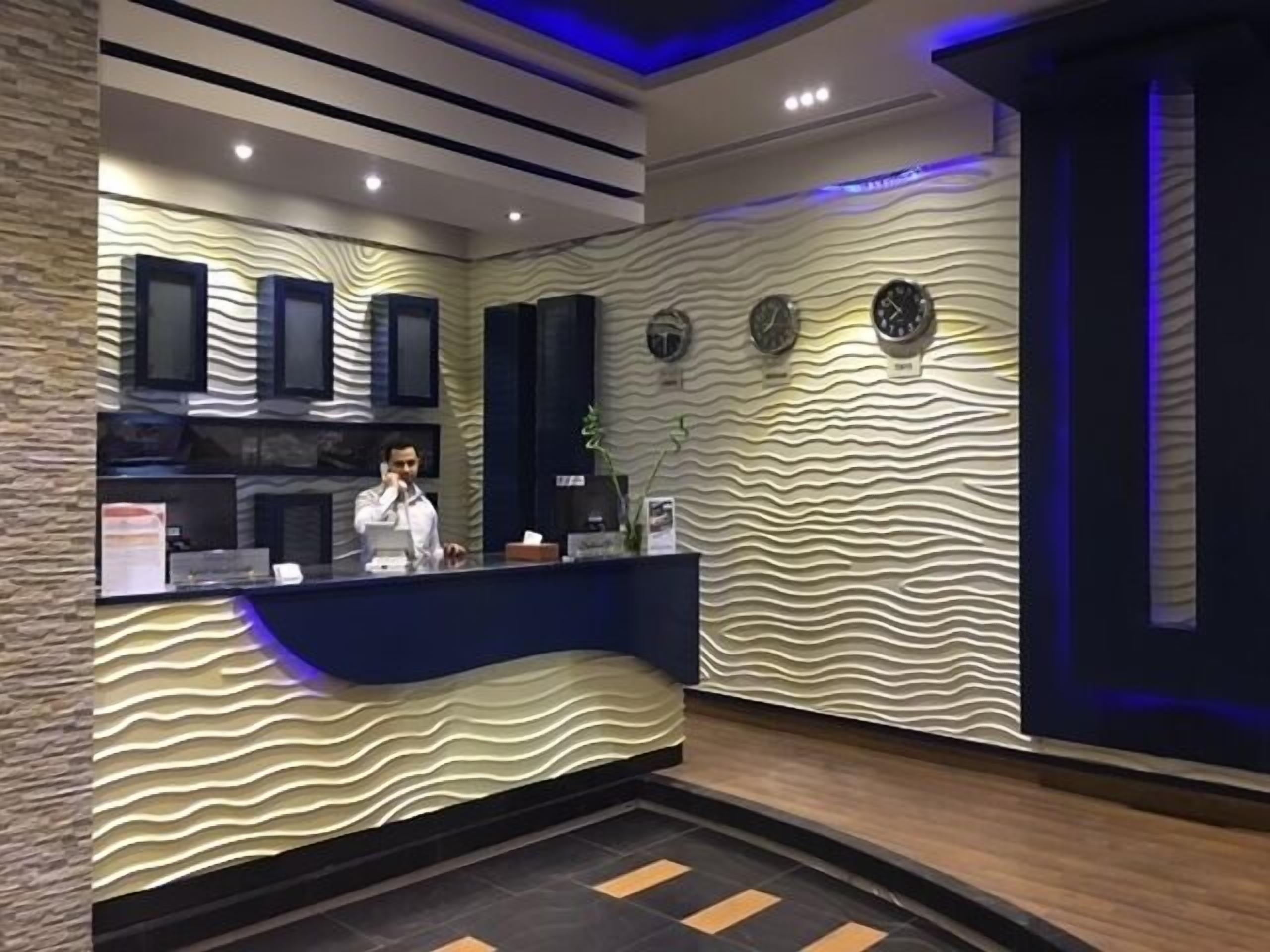 Un comptoir d’accueil au design moderne, caractérisé par un motif ondulé sur le mur et un comptoir bleu.
