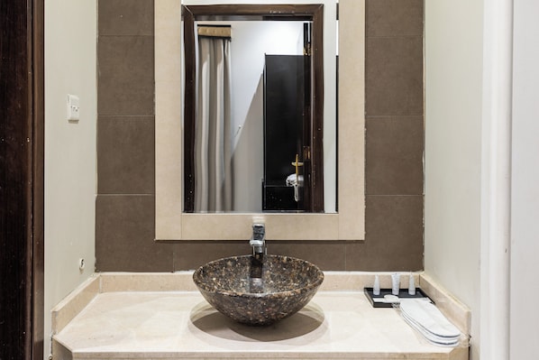 Une salle de bain avec un lavabo en granit, un miroir et un porte-serviettes.