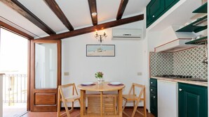 A compact kitchen with a wooden table and chairs, a built-in stove, and green cabinets. - Terrazza Bordonaro (Cefalù)