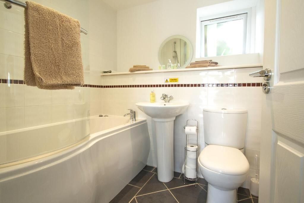 A bathroom with a bathtub, sink, toilet, and a window above the sink.