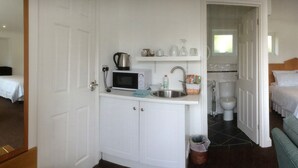 A hotel room with a bed, a desk with a computer, a TV, a microwave, and a kitchenette. - Gosfield Lake Resort (Halstead)