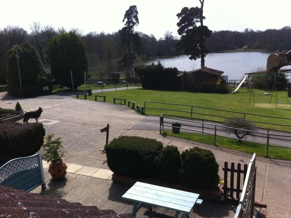 A park with a picnic table, benches, a playground, and a lake.