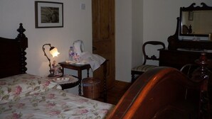 A bedroom with a bed, a nightstand, a dresser, a chair, and a wooden door. - Lisnafillan Lodge (Ballymena)