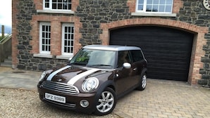 A Mini Cooper parked in front of a stone building with a garage. - Lisnafillan Lodge (Ballymena)
