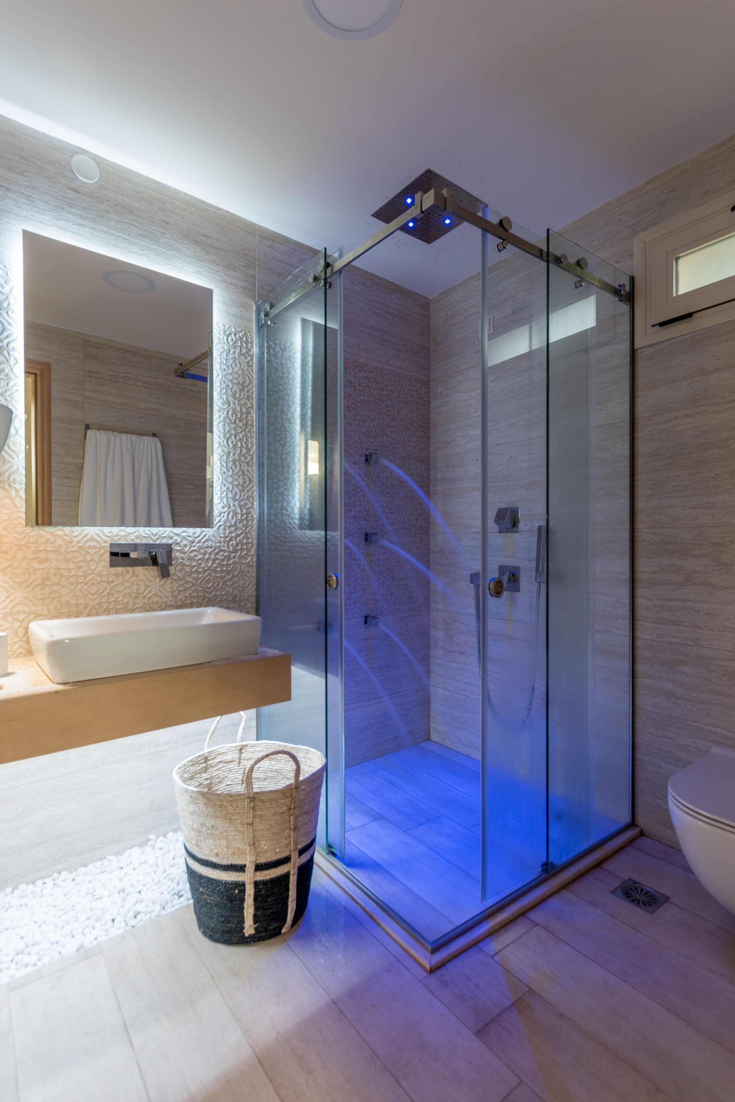 Un baño moderno con ducha de vidrio, tocador de madera y un espejo grande.