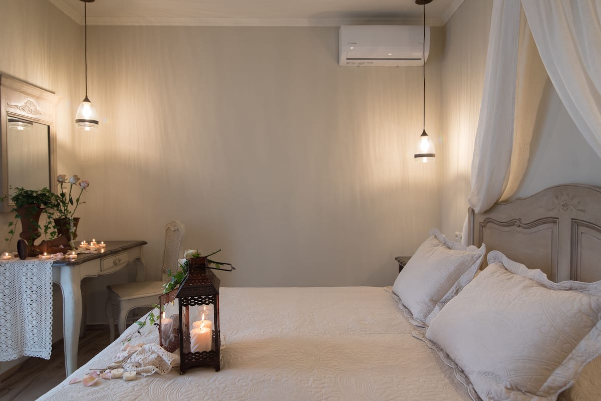 A bedroom with a bed, bedside table, lamp, and a mirror.